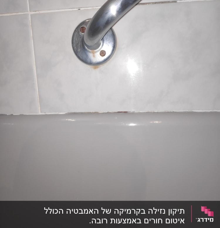 ידית מתכת על קיר אריחים ליד אמבטיה